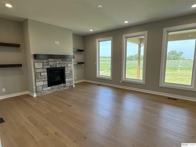 unfurnished living room featuring light wood-type flooring and a stone fireplace