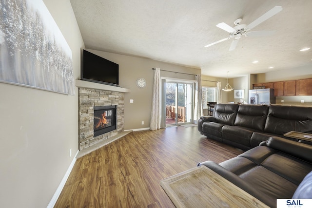 living room with a fireplace, wood-type flooring, a textured ceiling, and ceiling fan