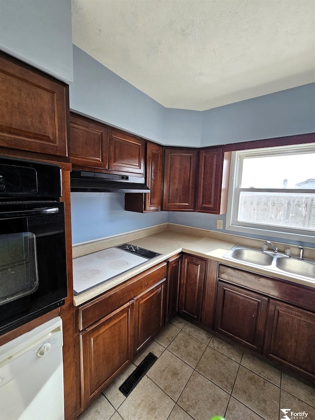 kitchen with dark brown cabinetry, sink, white appliances, and a textured ceiling