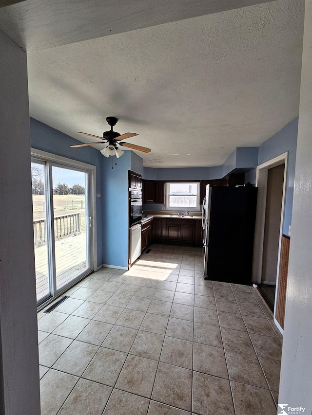 kitchen with light tile patterned flooring, ceiling fan, stainless steel fridge, and a textured ceiling