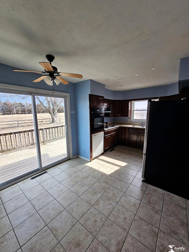 kitchen featuring sink, light tile patterned floors, a textured ceiling, and stainless steel refrigerator