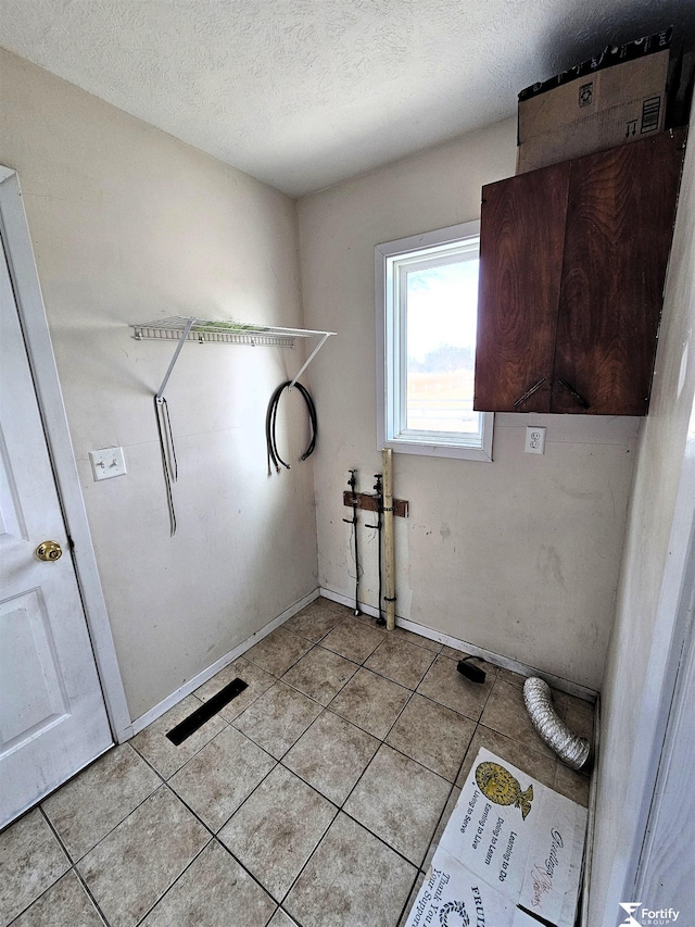 clothes washing area with light tile patterned flooring and a textured ceiling