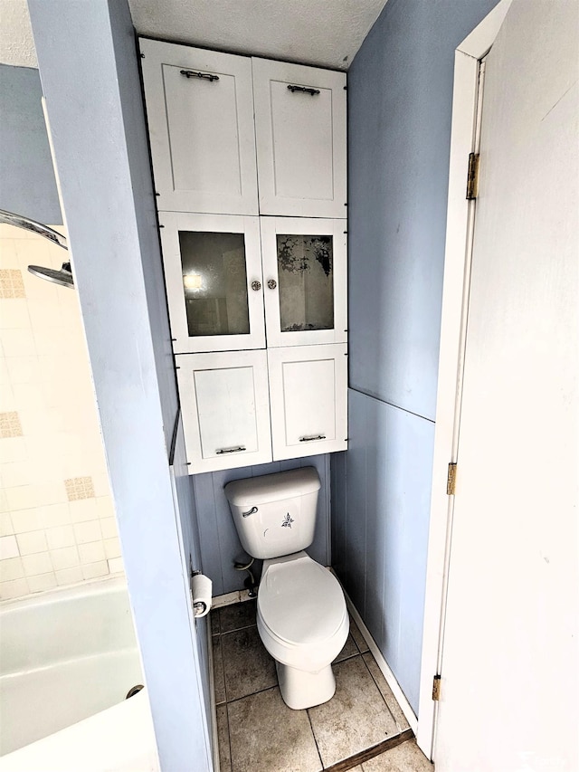 bathroom with tile patterned floors, toilet, and a tub