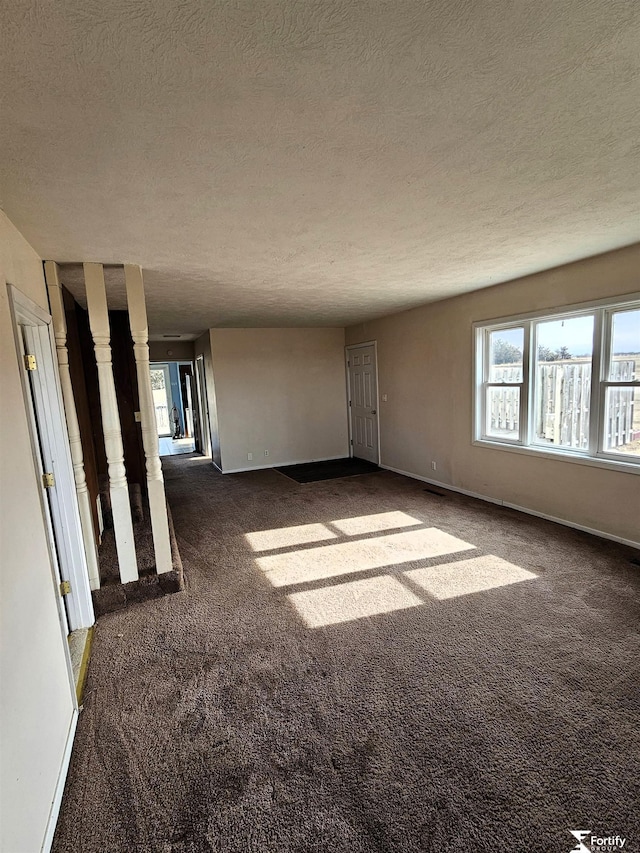 spare room with a textured ceiling and dark carpet