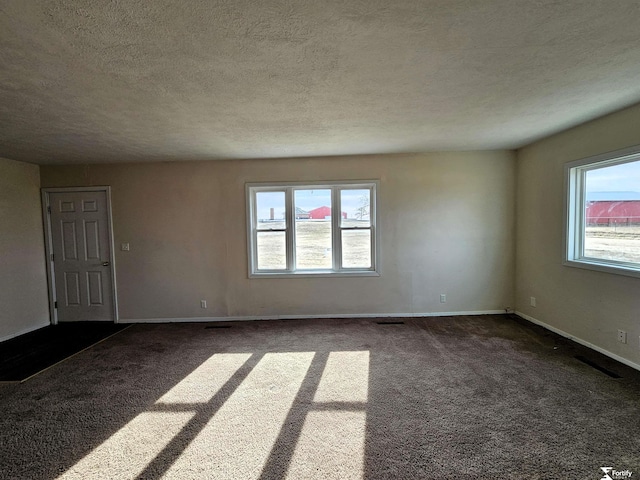 spare room featuring a textured ceiling and dark carpet