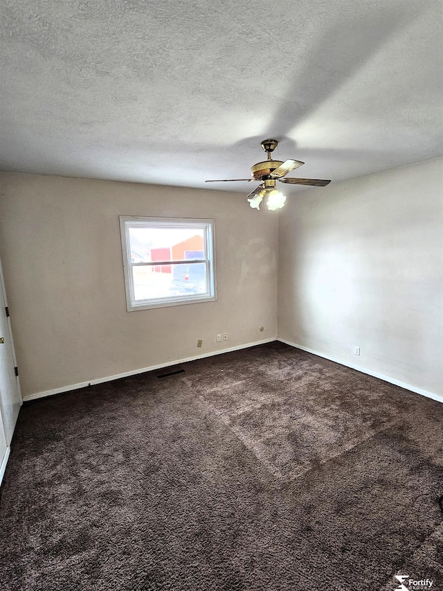 empty room with ceiling fan, a textured ceiling, and dark colored carpet