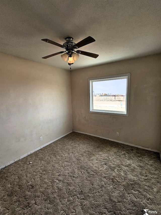 empty room featuring ceiling fan, a textured ceiling, and dark carpet