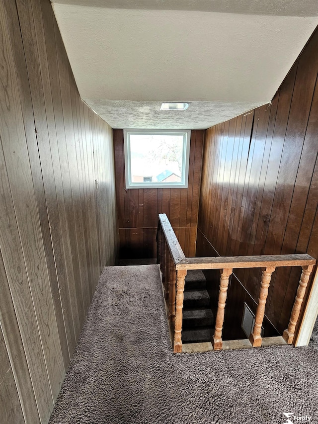 stairs featuring a textured ceiling and wooden walls