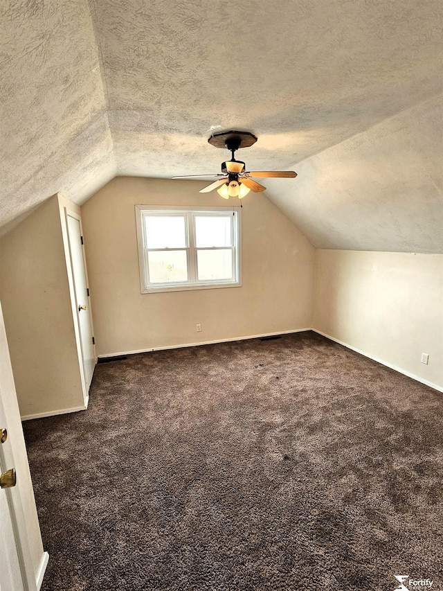 bonus room featuring vaulted ceiling, dark carpet, and a textured ceiling