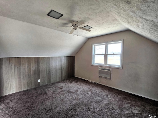 bonus room with wooden walls, carpet flooring, a wall mounted air conditioner, a textured ceiling, and vaulted ceiling