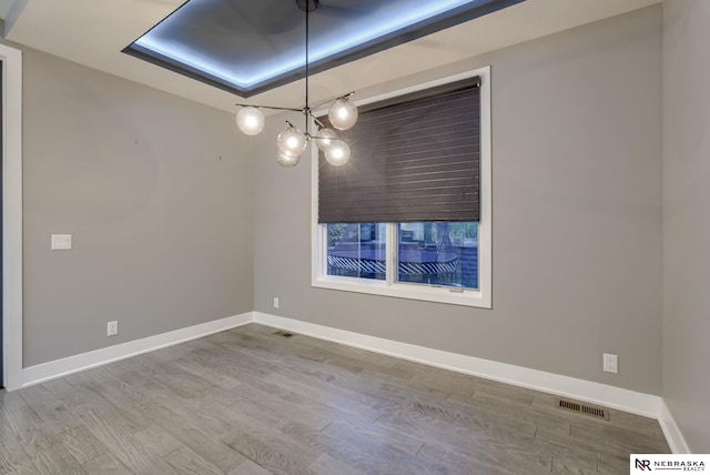 empty room featuring wood finished floors, visible vents, and baseboards