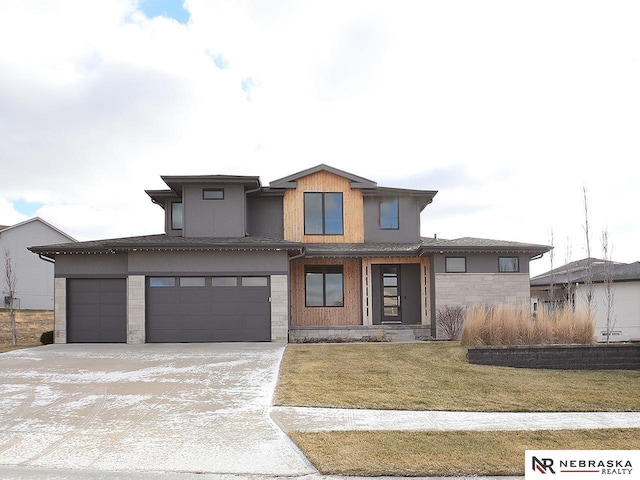 prairie-style home featuring a garage, concrete driveway, and a front yard