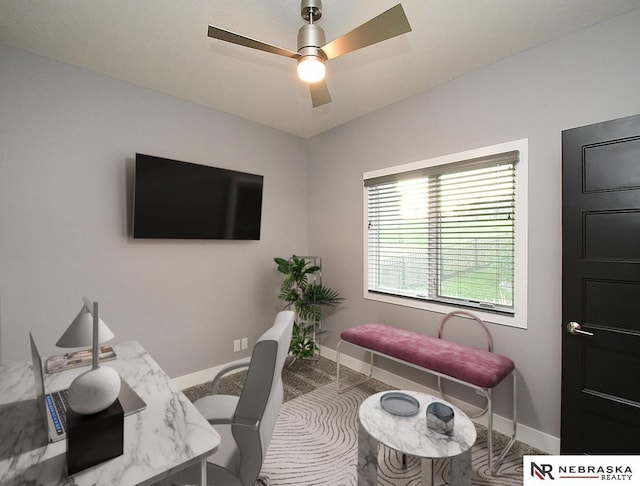 office area with a ceiling fan and baseboards