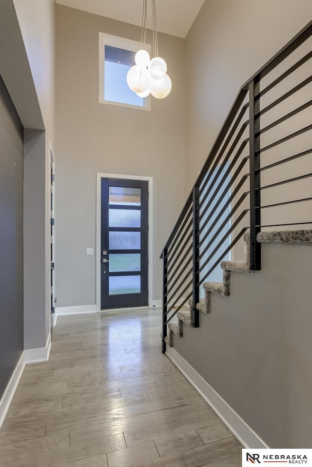 entryway featuring a chandelier, a high ceiling, light hardwood / wood-style floors, and a healthy amount of sunlight