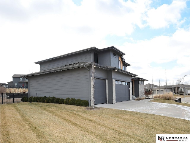 view of side of property with concrete driveway, a lawn, an attached garage, and fence