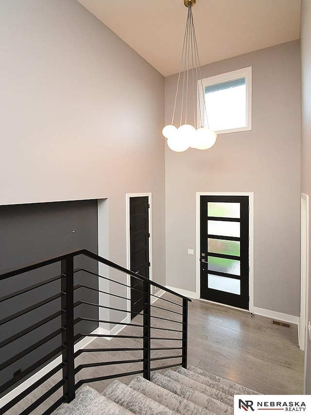 entryway featuring a towering ceiling, light hardwood / wood-style floors, an inviting chandelier, and a healthy amount of sunlight