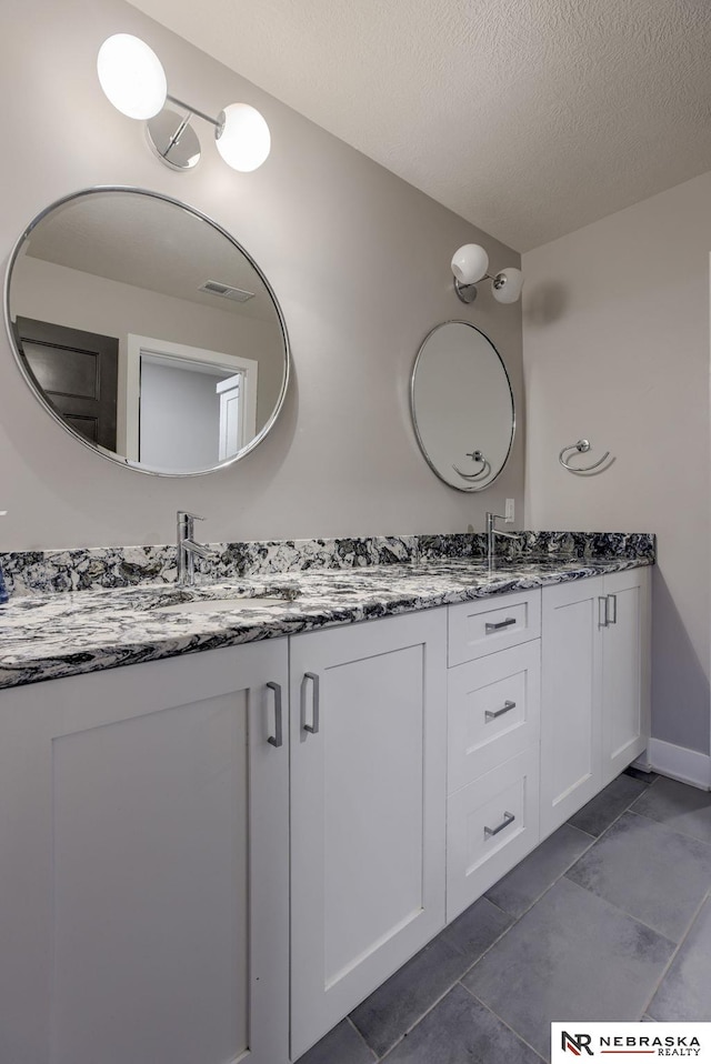 bathroom featuring tile patterned flooring, vanity, and a textured ceiling