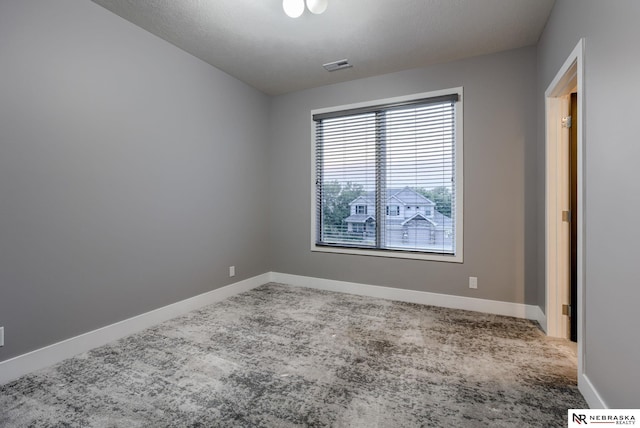 carpeted spare room with visible vents and baseboards