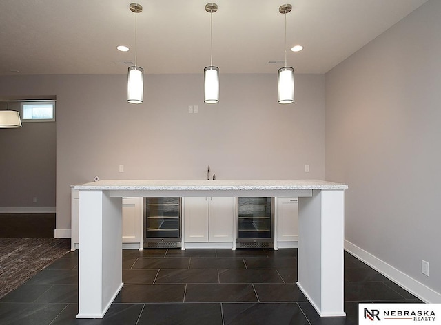 bar with wine cooler, white cabinetry, hanging light fixtures, and dark tile patterned flooring