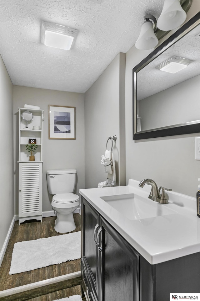 bathroom featuring a textured ceiling, toilet, vanity, and wood-type flooring