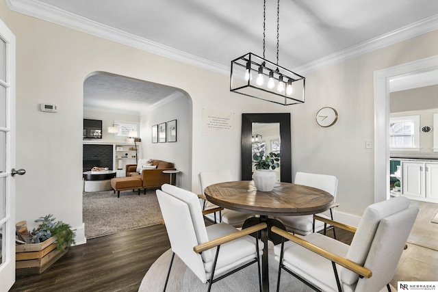 dining room with a fireplace, crown molding, and dark hardwood / wood-style flooring