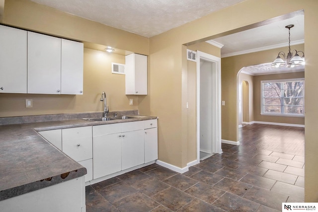 kitchen with a textured ceiling, sink, decorative light fixtures, a notable chandelier, and white cabinets