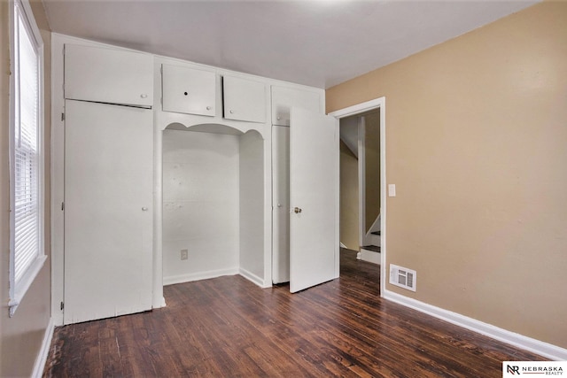 unfurnished bedroom featuring dark hardwood / wood-style floors and a closet