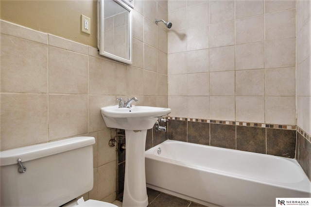 bathroom with tile patterned floors, toilet, and tile walls