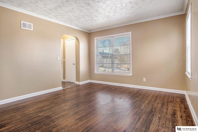 empty room featuring a textured ceiling, dark hardwood / wood-style flooring, and crown molding