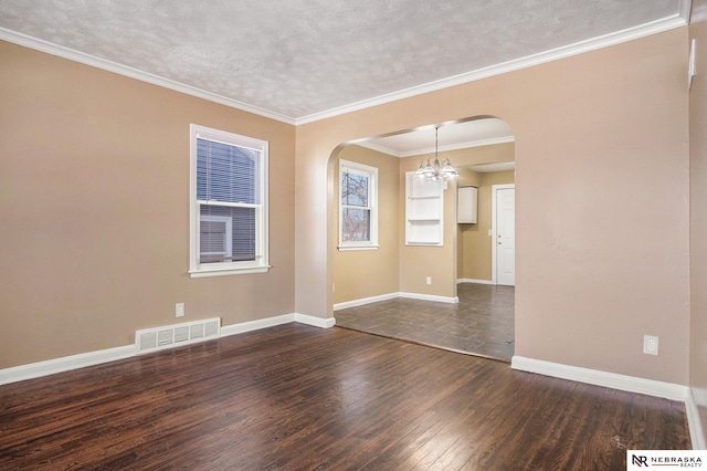 empty room featuring a notable chandelier, dark wood-type flooring, a textured ceiling, and ornamental molding