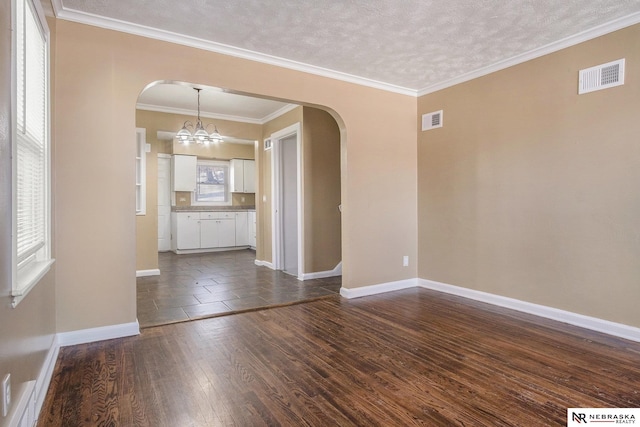 spare room with a textured ceiling, crown molding, a chandelier, and dark hardwood / wood-style floors