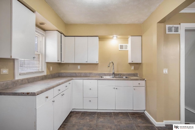 kitchen with white cabinetry, sink, and a textured ceiling