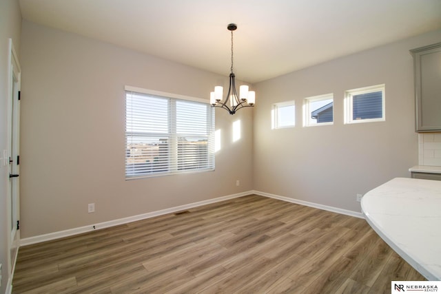 unfurnished dining area with dark wood-type flooring and an inviting chandelier