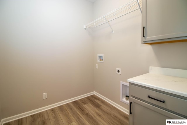 washroom featuring cabinets, washer hookup, hookup for an electric dryer, and light hardwood / wood-style flooring