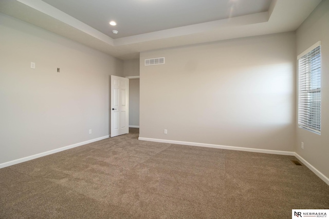 carpeted empty room featuring a raised ceiling