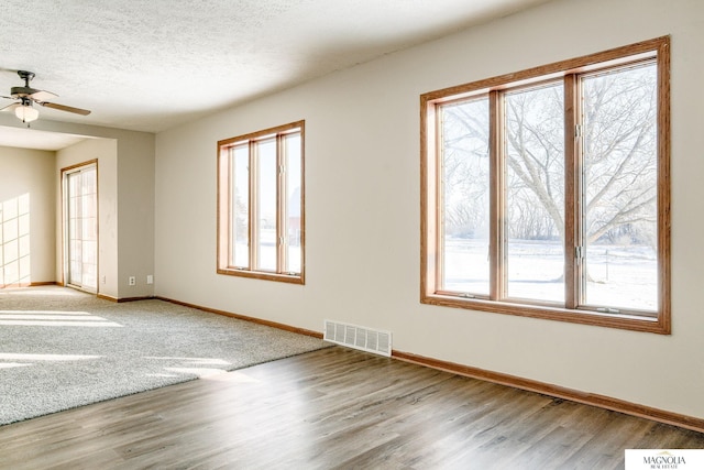 spare room with hardwood / wood-style floors, ceiling fan, a healthy amount of sunlight, and a textured ceiling