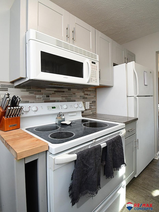 kitchen featuring tasteful backsplash, dark hardwood / wood-style flooring, a textured ceiling, white appliances, and white cabinets