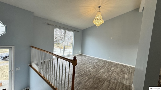 stairway with hardwood / wood-style floors, vaulted ceiling, and an inviting chandelier