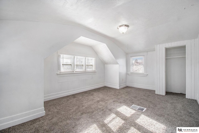 bonus room featuring carpet, a textured ceiling, and lofted ceiling