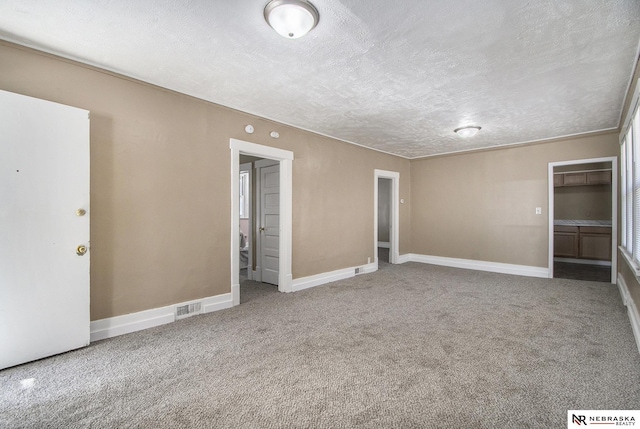 unfurnished bedroom featuring carpet, a textured ceiling, and a spacious closet