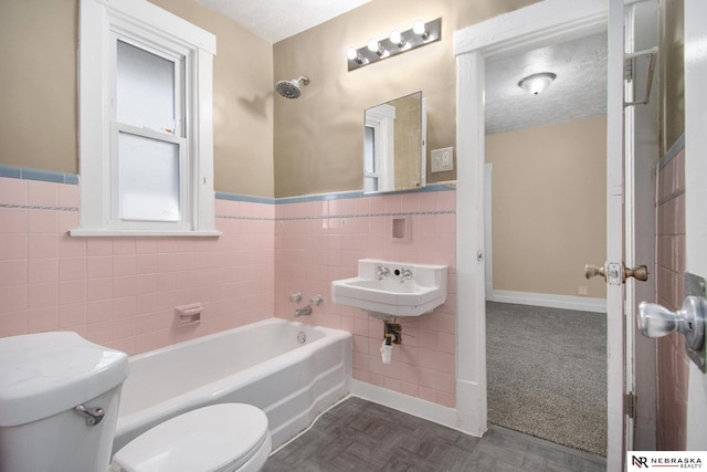 bathroom with a textured ceiling, sink, tile walls, and toilet