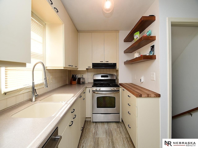 kitchen featuring sink, light hardwood / wood-style flooring, appliances with stainless steel finishes, tasteful backsplash, and white cabinetry