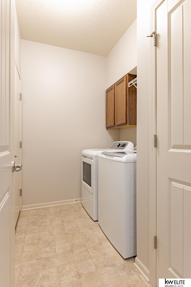 washroom featuring cabinets, a textured ceiling, and independent washer and dryer