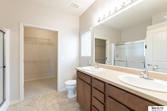 bathroom featuring a shower with door, vanity, and toilet