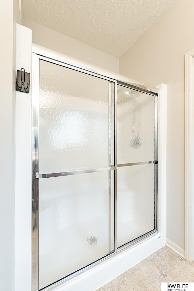 bathroom featuring a textured ceiling and an enclosed shower