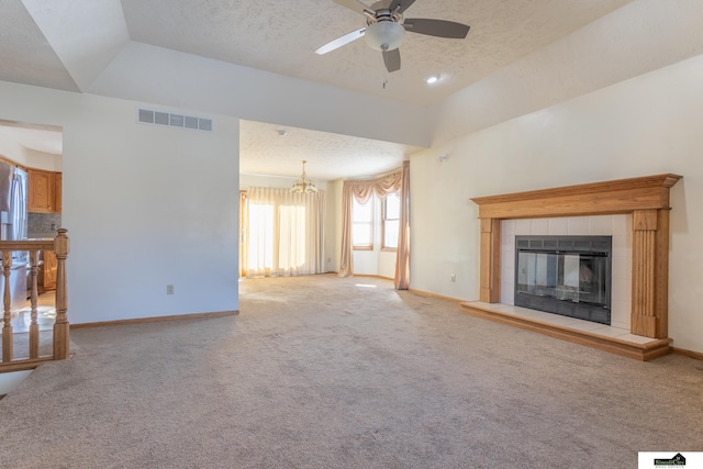 unfurnished living room featuring a textured ceiling, light carpet, a fireplace, and ceiling fan with notable chandelier