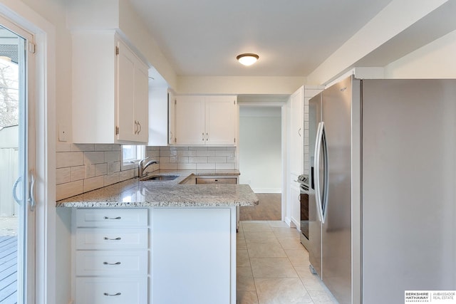 kitchen with appliances with stainless steel finishes, light stone countertops, decorative backsplash, sink, and white cabinetry