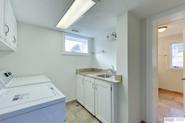 laundry room featuring sink, light tile patterned flooring, washing machine and clothes dryer, and cabinets