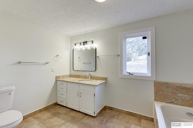 bathroom featuring toilet, a textured ceiling, a tub to relax in, and vanity