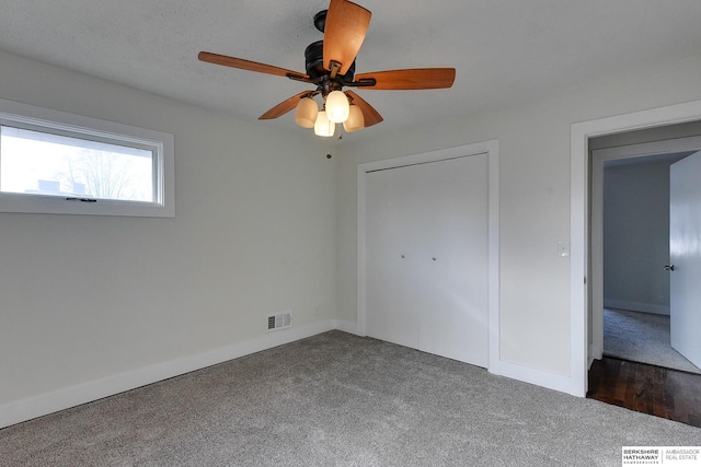 unfurnished bedroom featuring ceiling fan and dark colored carpet